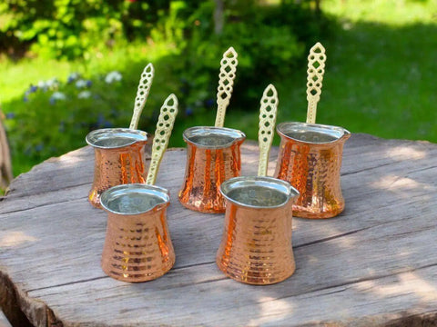 Handcrafted Copper Turkish Coffee Maker With Five Pots on wooden surface outdoors