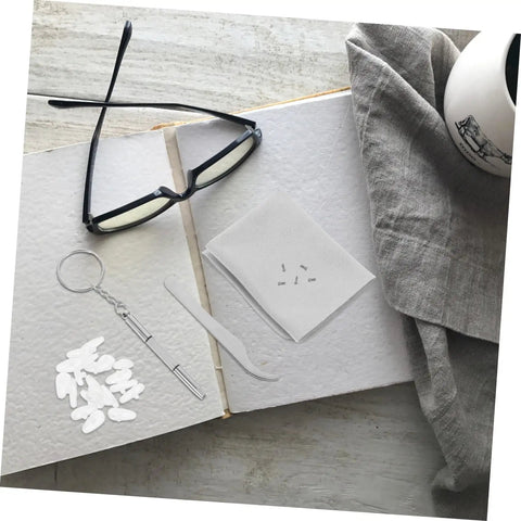 All In One Eyeglasses Repair Kit With Silicone Nose Pads, Mini Screwdrivers, Tweezers And Tiny Screws displayed on a book.