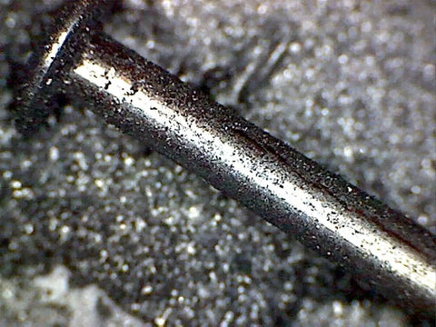Close-up of a metal axle coated with Graphite Dry Lube For Wood Derby Cars With Tungsten Moly Boron Blend.