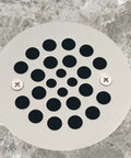 Solid Heavy Duty Shower Strainer Drain Cover With Screw In Trim Set Rust Resistant Brushed Nickel Finish installed on gray flooring.