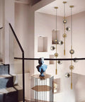 Lit Four Light Smoky Gray Glass Globe Pendant Light With Adjustable Cord And Gold Accents For Kitchen Island Bar Modern LED Chandelier Mid Century Industrial Ceiling Fixture hanging in a modern staircase area.