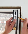 Person using the Straight Shooter Nine In One Measuring And Marking Tool featuring dual levels against a wall to mark measurements.