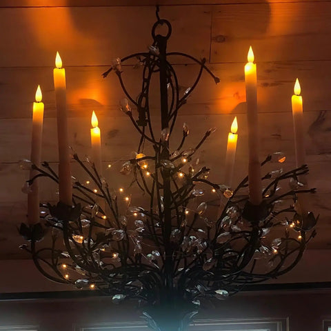 Chandelier adorned with Eight Inch Ivory Flameless Taper Candles With Remote And Timer, flickering flame effect and real wax look