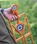Man holding Double Paddle Spinner Shooting Target with 3 inch and 4.5 inch spinning targets, no reset, steel four-leg stand.