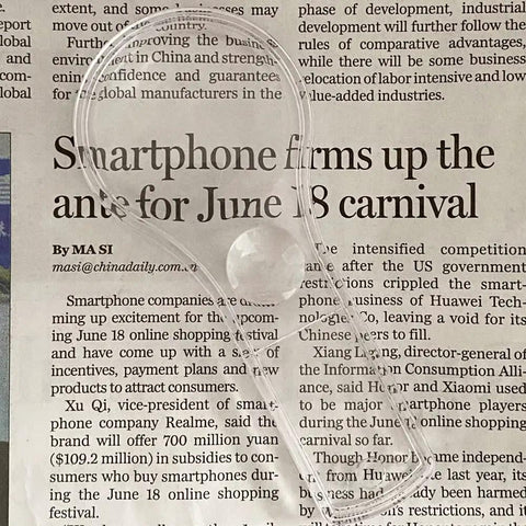Close-up of handheld magnifier from 24 Pack Handheld Magnifiers With 5X And 15X Lenses over newspaper text.