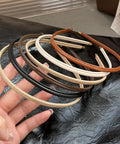 Five piece set of Premium Skinny Leather Headbands For Women in neutral shades held in hand, soft top grain leather accessories.