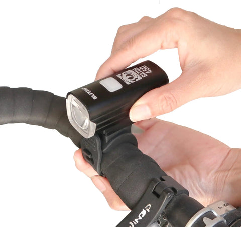 Person installing Ultra Bright Front And Rear USB Rechargeable Bike Light Set for night riding on handlebars.
