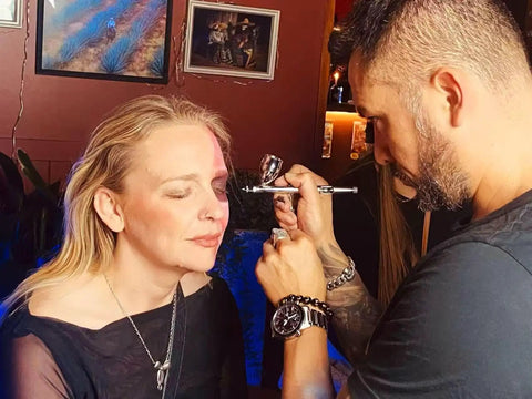 Makeup artist using Ultra Quiet Airbrush Compressor With Built In Air Tank Portable Lightweight 5.5lb Unit on model's face
