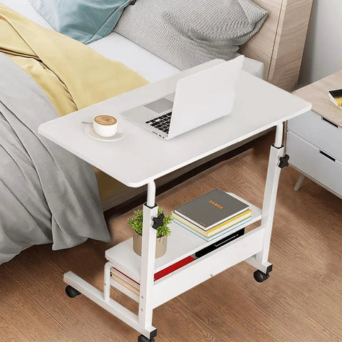 Height Adjustable Mobile Computer Desk With Wheels For Small Spaces And Corner Setup Laptop Table 31.5 Inch Desktop White Portable Home Office Study Desk With Storage And Convenient Gaming And Writing Space with a laptop and coffee cup on top next to a bed.