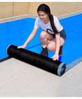 Real Deal Self Adhesive Roofing Felt Roll With Aluminum Foil Backing being applied by a woman on a flat roof surface.