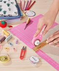 45mm Rotary Cutter With 5 Extra Blades, Ergonomic Grip, Safety Lock, The Real Deal For Fabric Leather Crafting Sewing And Quilting, Cuts Through Multiple Layers Like Butter, Left Or Right Hand, Pink, cutting fabric on a pink mat with sewing tools