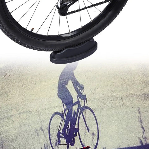 Front Wheel Riser Block For Indoor Bike Trainer Stand showing non-slip pad and shadow of a cyclist.