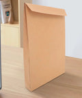 Kraft Self Seal Mailing Envelopes 238x335x40mm With Double Sided Adhesive Tape on a desk beside a laptop