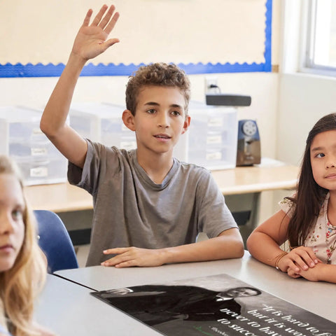 Student raising hand in classroom with Eight American Presidents Quotes Poster Set For Classrooms And Homes on desk.