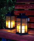 Two Pack Lit Solar Powered Outdoor Hanging Lanterns With Waterproof LED Flickering Flameless Candles, black on bench at night