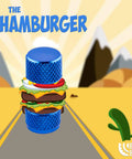 Blue knurled valve cap designed as a hamburger, featuring layers of colorful toppings against a desert road scene.