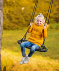 Child enjoying Saucer Tree Swing For Kids, 24 Inch Net Seat Disc Round Swing in a fall backyard setting