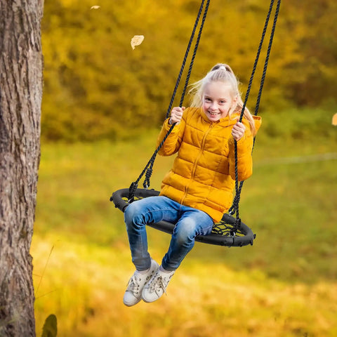 Child enjoying Saucer Tree Swing For Kids, 24 Inch Net Seat Disc Round Swing in a fall backyard setting