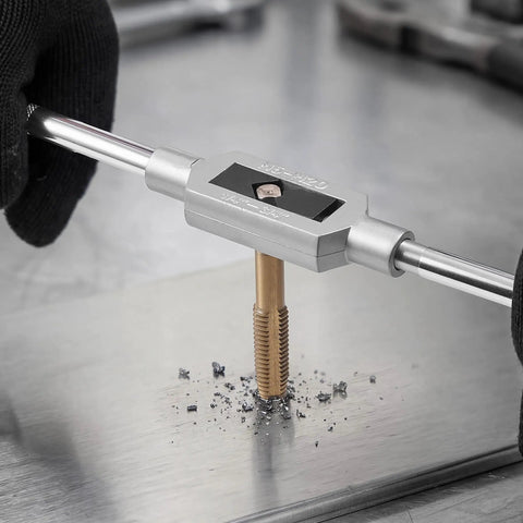 Person using Beefy Titanium Coated Steel Tap And Die Set for threading metal with a wrench on a steel surface.