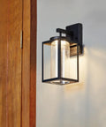 Capulet Amber Glass Center Column Outdoor Indoor Wall Sconce With LED Black Finish on grey wall near wooden door
