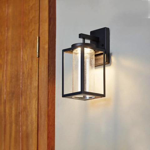 Capulet Amber Glass Center Column Outdoor Indoor Wall Sconce With LED Black Finish on grey wall near wooden door