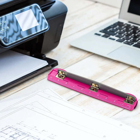 3 Hole Punch For Ring Binders With Built In Ruler on wooden desk near laptop and printer, deep pink ABS plastic, stainless steel punch heads