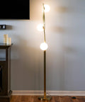 Nola Mid Century Modern 3 Globe Floor Lamp For Living Room And Office in gold finish, standing next to a console table.