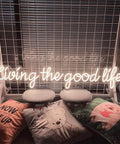 Living The Good Life LED Neon Sign Custom Personalized Home Wall Decor Large 30 Inch Indoor Light with cushions and chairs.