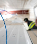 Collapsible Three Foot Cable Grabbing And Reaching Fish Pole pulling blue wire in ceiling installation with worker nearby.