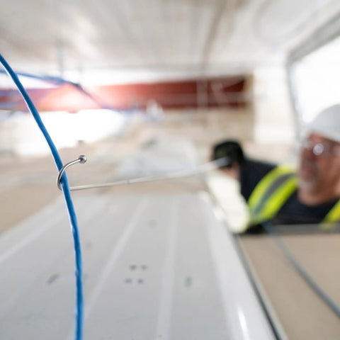 Collapsible Three Foot Cable Grabbing And Reaching Fish Pole pulling blue wire in ceiling installation with worker nearby.