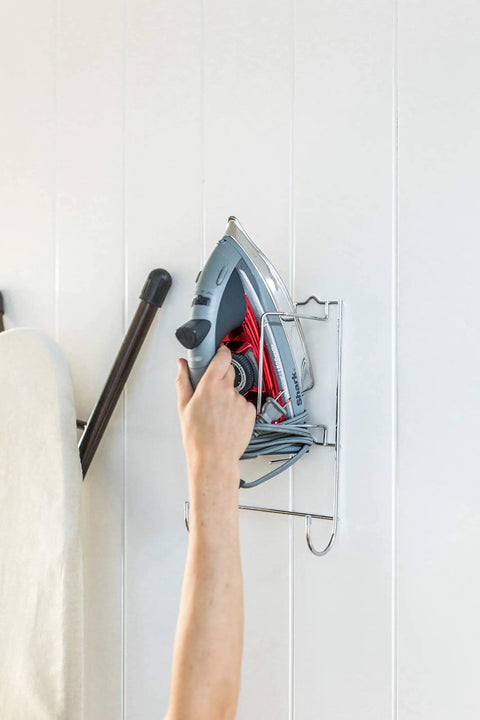 Person placing iron on Super Handy Ironing Board Holder Wall Mount for Laundry Room keeps iron and board together on wall.