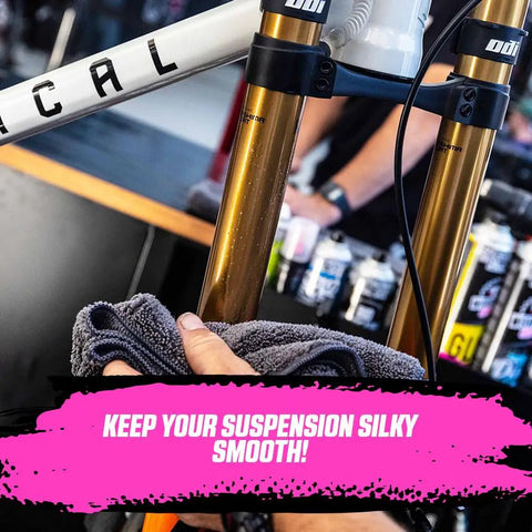 Applying Silky Suspension Serum 100ml Protective Spray to bike shocks to reduce stiction and friction, repelling dirt.