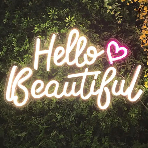 Hello Beautiful Neon Sign For Girl's Room Wall Decor With Dimmer Switch Romantic Neon Light For Weddings Valentine's Day Parties Gifts 12V Warm White With Power Adapter Included glowing on a green leaf wall.