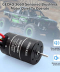 Close-up of Gecko 3660 brushless motor with RC rock crawler in background, showcasing drive system for 1/10 scale models.