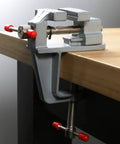 Built Tough Mini Table Vise Crafted From Premium Aluminum Alloy Featuring Wide Flat Jaws For A Killer Hold Quick Bolt Down Setup and Compact Profile mounted on a workbench.