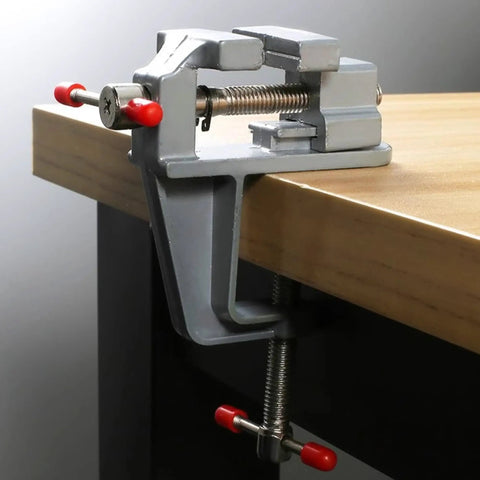 Built Tough Mini Table Vise Crafted From Premium Aluminum Alloy Featuring Wide Flat Jaws For A Killer Hold Quick Bolt Down Setup and Compact Profile mounted on a workbench.