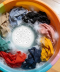 Portable USB Powered Mini Washing Machine For Travel And RV Adventures filled with colorful clothes in sudsy water.