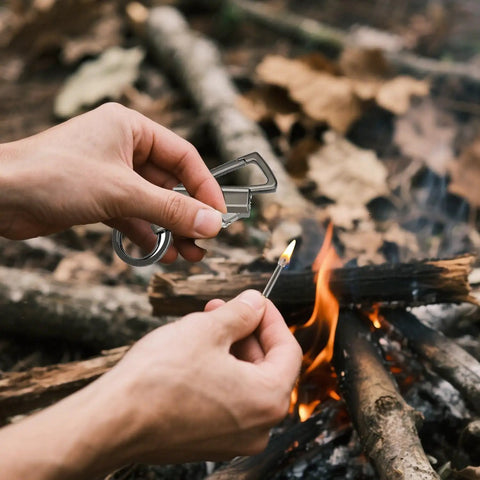 Person using All In One Multitool Lighter Keychain With Bottle Opener, Reusable Waterproof Fire Starter For Outdoor Survival near campfire.