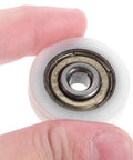 Smooth 1.5 Inch Small Ball Bearing Rollers With Deep Groove Steel Design For Skateboard Wheels and Industrial Machinery Gear, Featuring Durable Nylon Construction For Long Lasting Performance. Hand holding a white roller bearing.