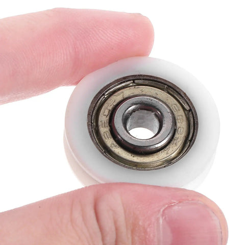 Smooth 1.5 Inch Small Ball Bearing Rollers With Deep Groove Steel Design For Skateboard Wheels and Industrial Machinery Gear, Featuring Durable Nylon Construction For Long Lasting Performance. Hand holding a white roller bearing.