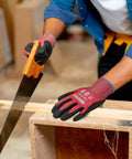 Person wearing Cut Resistant Nitrile Coated Safety Gloves With Firm Grip ANSI Cut A4 KG22N, sawing wood in a workshop.
