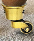 Close-up of a vintage zinc alloy swivel caster with 1-3/4 inch OD, antique brass bronze finish, attached to furniture leg.