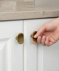 Hand showing Six Pack Antique Brass Zinc Alloy Cabinet Knobs Heavy Duty Solid Square Pulls on white cabinet door