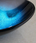 Close-up of Blue 21 Inch Oval Glass Vessel Sink With Faucet And Pop Up Drain Above Counter Modern Bathroom Vanity Setup.