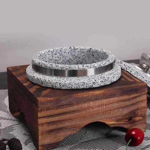 Heavy Duty Granite Clay Pot With Wood Base For Korean Dolsot Bibimbap And Donabe Style Dishes on rustic wooden trivet, side view.