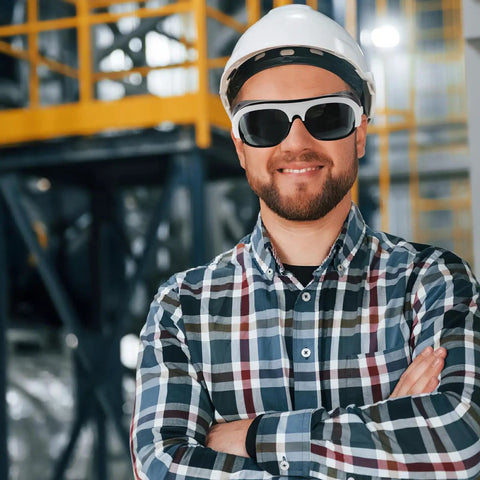 Kickass Welding Safety Glasses Featuring Wide Side Coverage And Mask Compatible Design For Total Eye Protection With Ridiculously Comfortable Fit Guaranteed worn by a smiling man in a hard hat.