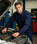 Kick Ass Heavy Duty Men's Long Sleeve Work Shirt And Custom Printed Industrial Uniform For Mechanics And Factory Crews Featuring Thick 100 Percent Cotton Gear, worn by a mechanic working on a car engine.