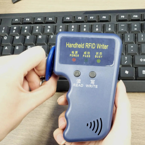Hands using Portable No Fuss Handheld 125KHz RFID Reader Writer Copier for T5577 and EM4305 Smart ID Card Duplicator near keyboard