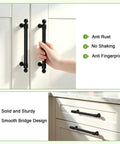 Hand holding 10 Pack 5 Inch Matte Black Cabinet Handles And Drawer Pulls with solid build on white cabinet door.
