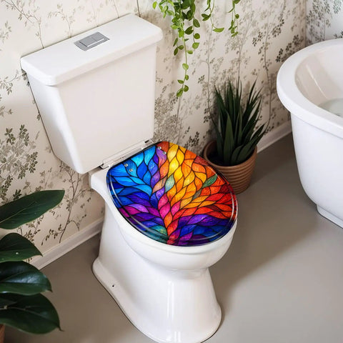 Round Colorful Stained Glass Effect Abstract Leaf Radiant Toilet Seat on a white toilet with lush green plants in the background.